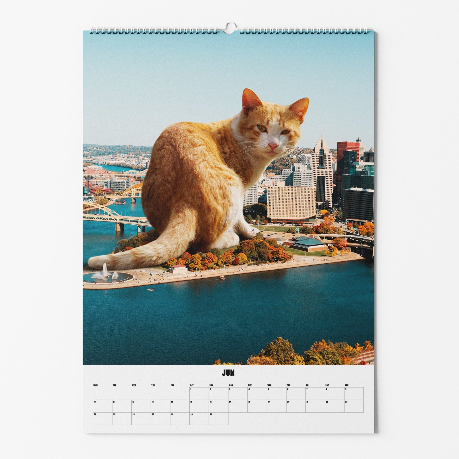 Riesige rote Katze sitzt auf einer Insel in einer Stadtlandschaft auf einem Kalenderbild für Juni.
