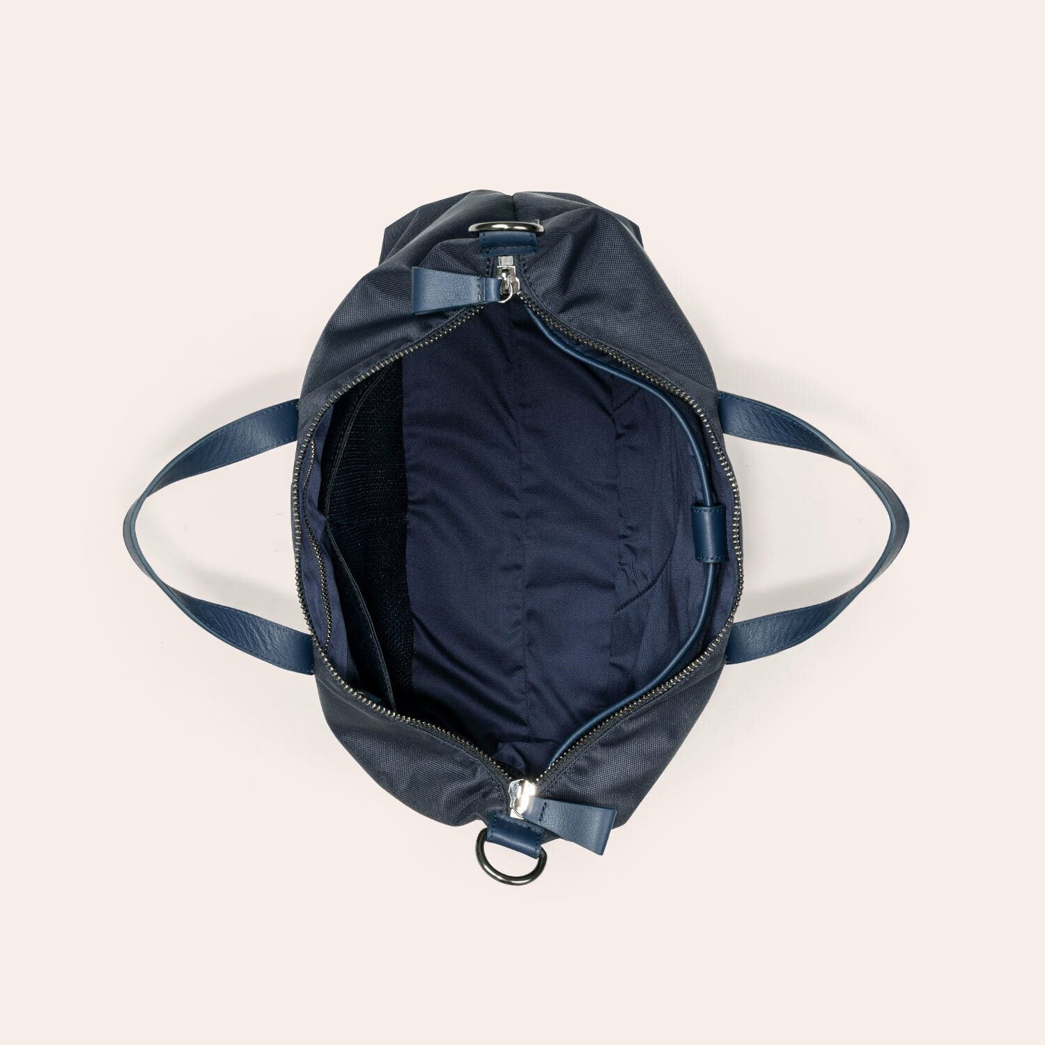 Draufsicht auf einen offenen marineblauen Seesack mit zwei Griffen, der den geräumigen, leeren, mit Stoff ausgekleideten Innenraum und eine kleine Innentasche auf einer Seite zeigt.