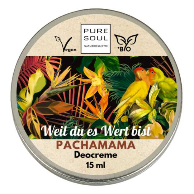 Eine runde Dose Pure Soul Pachamama Deodorant Creme, 15 ml, mit bunten tropischen Blättern und zwei Papageien auf dem Etikett. Der Text enthält Weil du es Wert bist, und Symbole für die Vegan- und Bio-Zertifizierung.