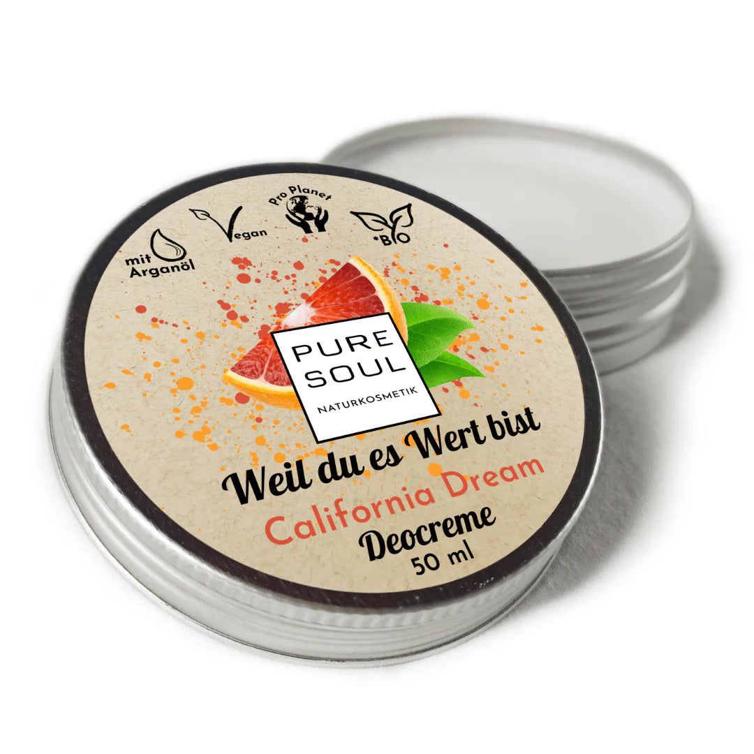 Eine runde Metalldose von PURE SOUL California Dream Deocreme (50 ml) mit einem beigen Etikett, auf dem eine Grapefruit abgebildet ist und Symbole für vegan, bio, ohne Plastik und Arganöl zu sehen sind. Der Deckel ist leicht geöffnet.