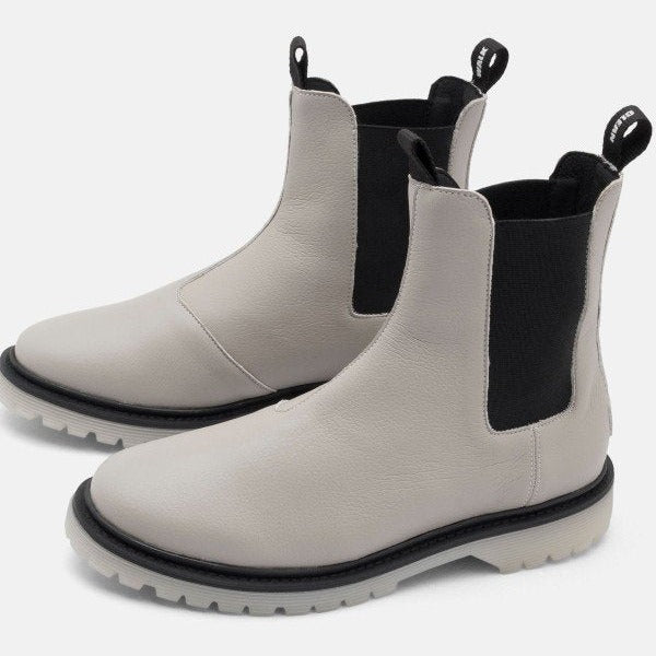 Zwei hellgraue Chelsea-Stiefel mit schwarzem elastischem Einsatz und Zuglaschen, auf einem weißen Hintergrund.