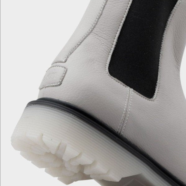 Nahaufnahme eines weißen Stiefels mit schwarzem elastischem Einsatz und dicker, strukturierter Sohle.