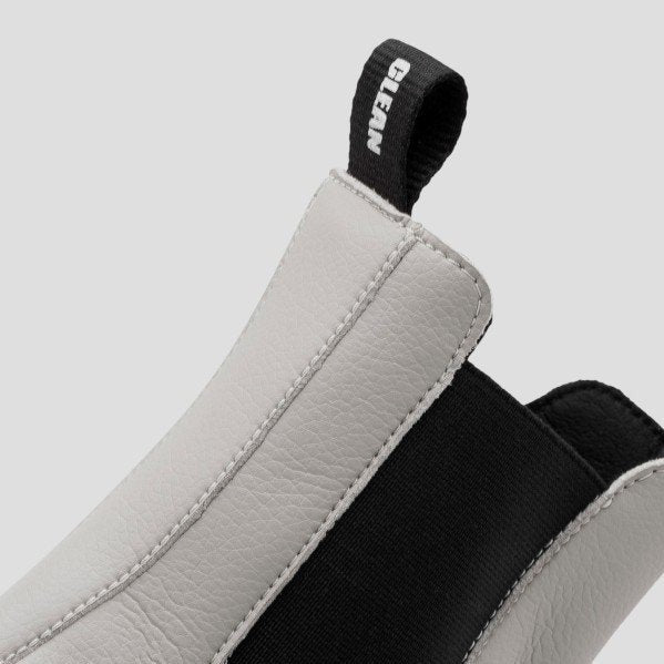 Detailaufnahme eines Stiefels mit weißem Leder, schwarzem Gummizug und einer schwarzen Schlaufe mit der Aufschrift "CLEAN".