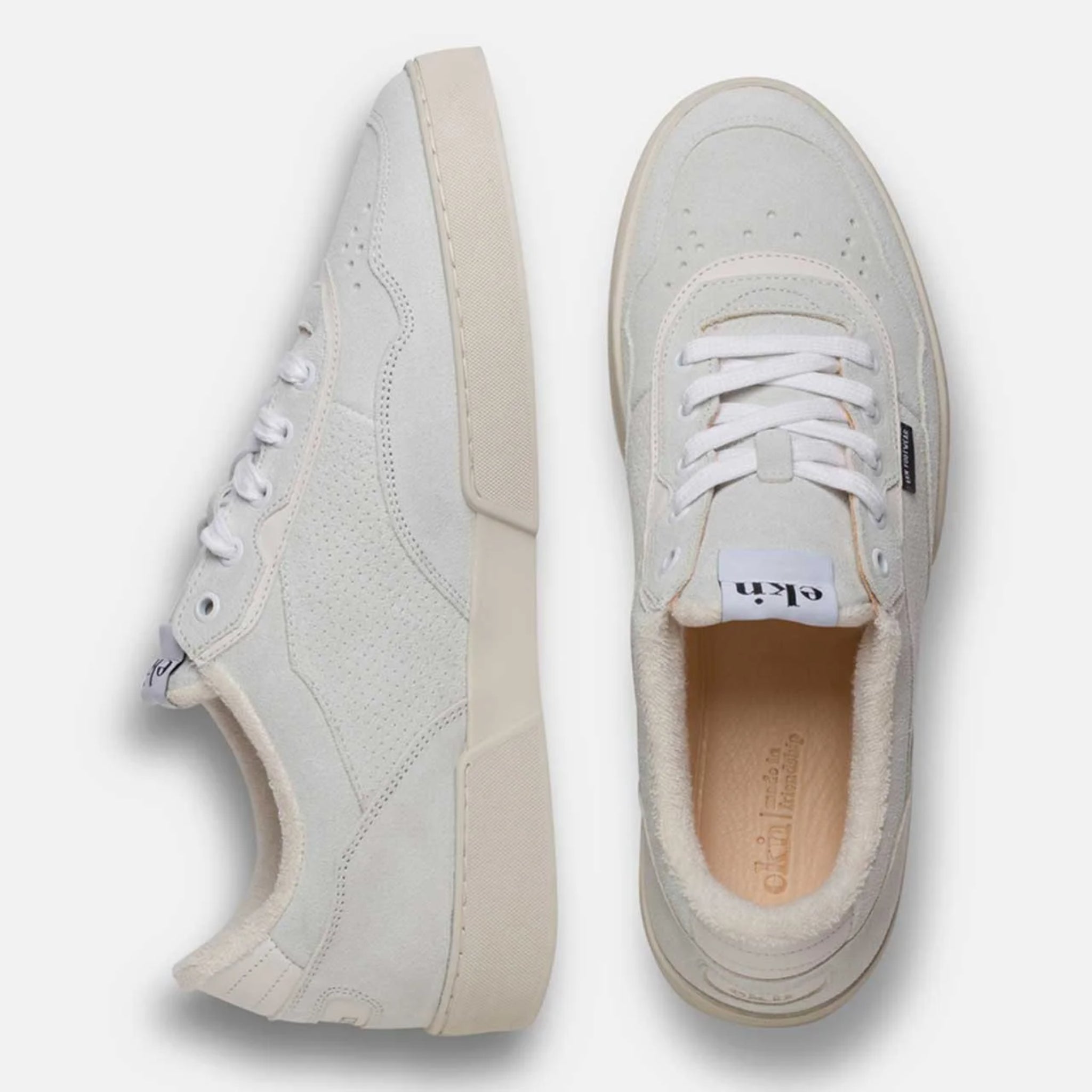 Zwei weiße Turnschuhe aus Leder, seitlich und von oben fotografiert, auf einem weißen Hintergrund.