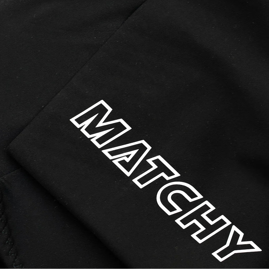 Eine Nahaufnahme von schwarzem Stoff mit sichtbaren Nähten und dem Wort MATCHY in fetten weißen Großbuchstaben entlang einer Kante.