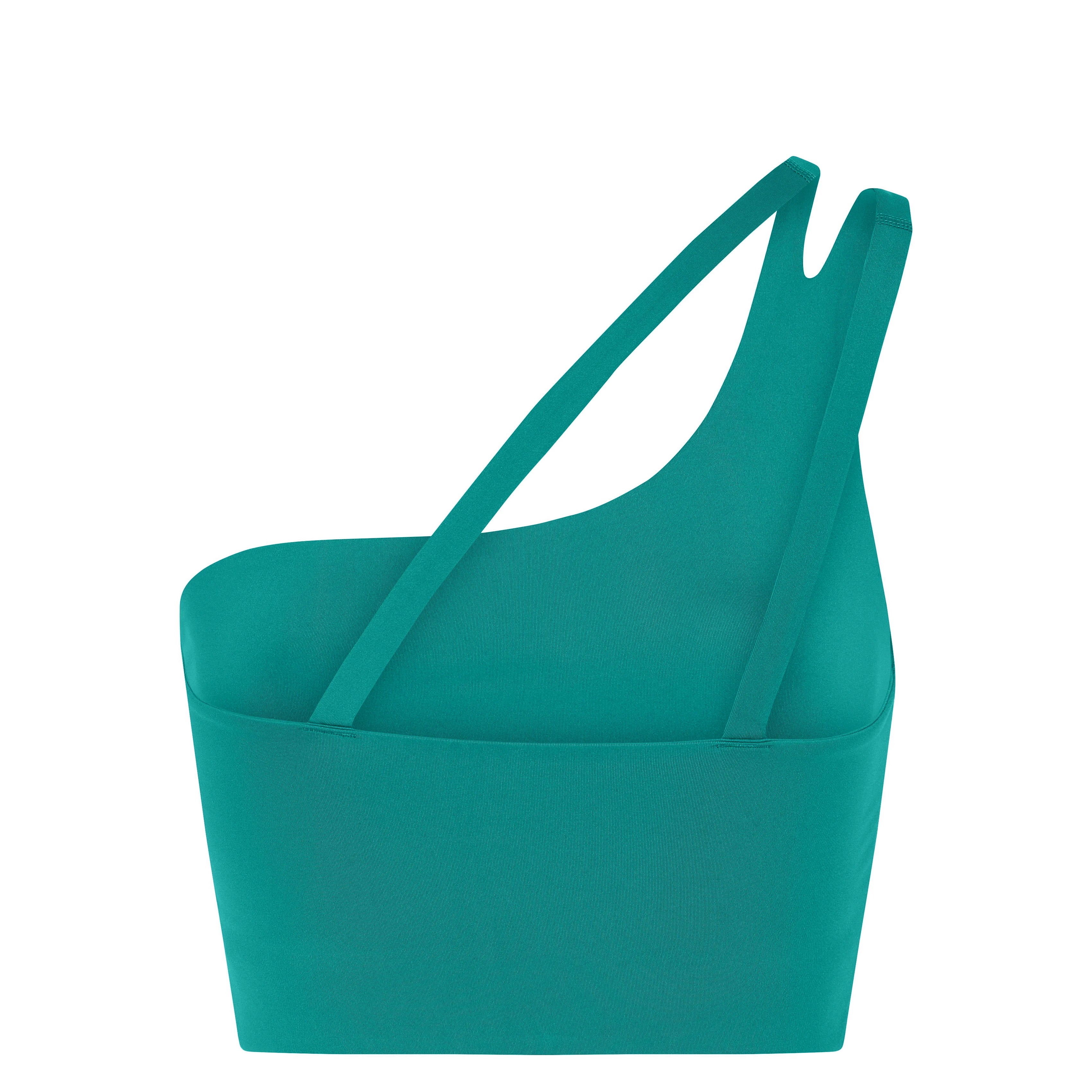 Eine tealfarbene, asymmetrische Handtasche mit zwei dünnen Schulterriemen und einem strukturierten, modernen Design wird vor einem weißen Hintergrund gezeigt.