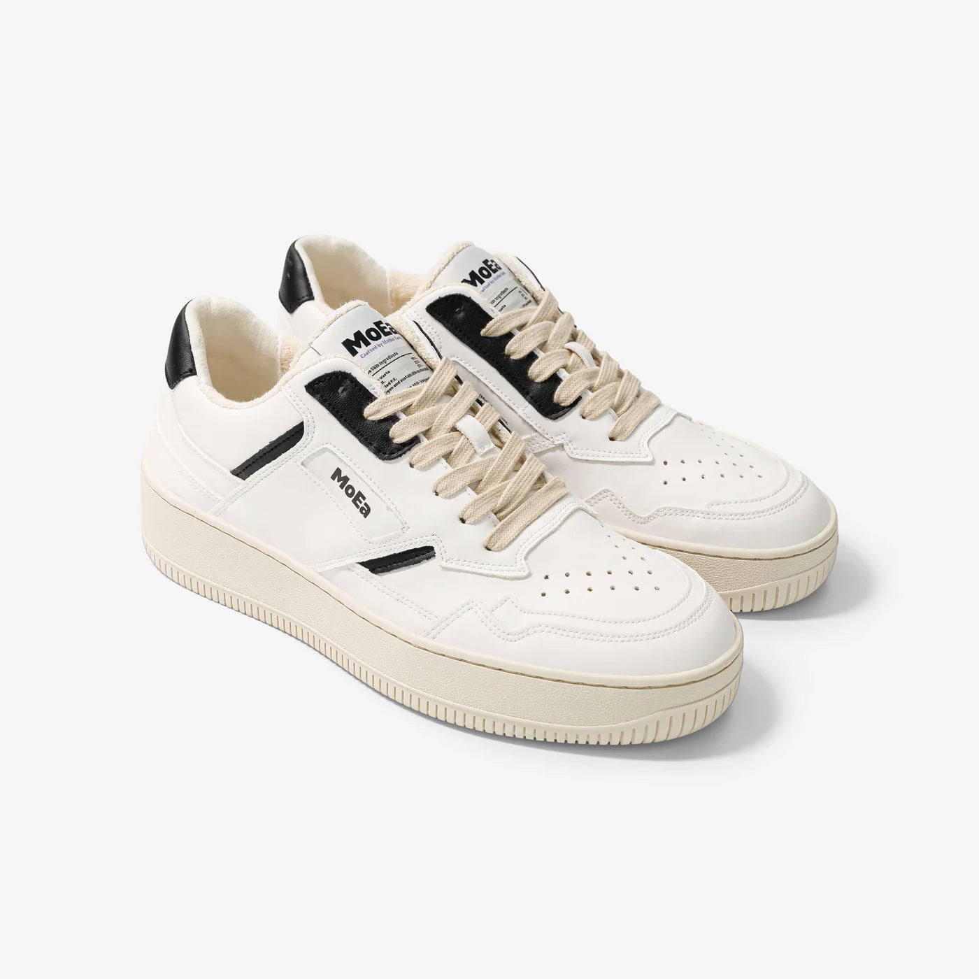 Ein Paar weiße Ledersneaker mit beiger Sohle, beigen Schnürsenkeln, schwarzen Akzenten an der Ferse und MoeS-Branding auf der Zunge und an der Seite, dargestellt auf weißem Hintergrund.