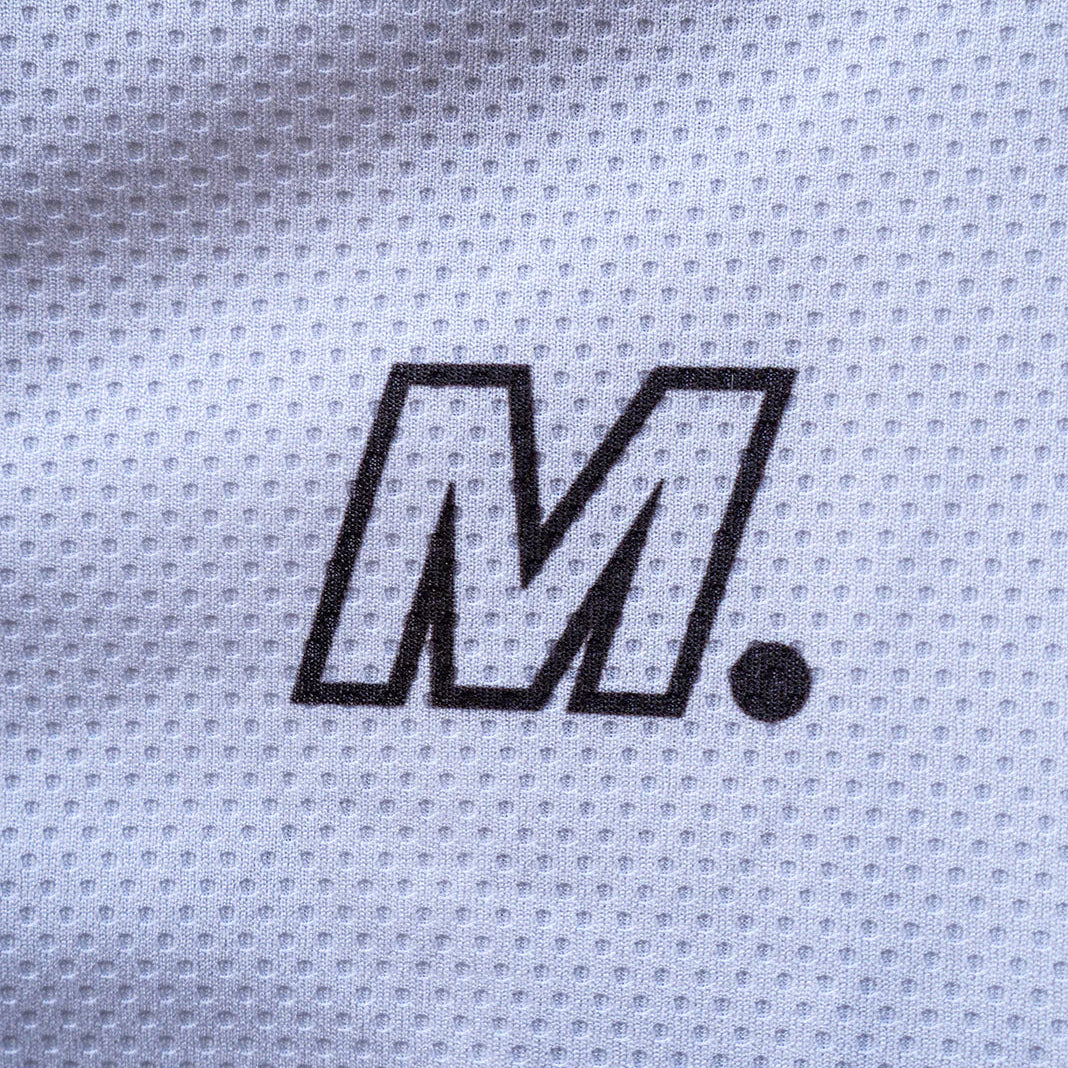 Nahaufnahme eines weißen, strukturierten Stoffes mit einem fetten, schwarzen Buchstaben M, gefolgt von einem Punkt, der in der Mitte des Stoffes aufgedruckt ist.