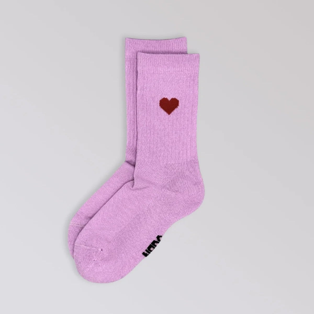 Ein Paar hellviolette Socken mit einem kleinen roten Herzmuster am oberen Rand auf hellgrauem Hintergrund.