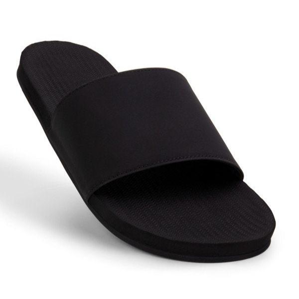 Schwarzer Einzelslipper mit breitem Riemen auf weißem Hintergrund.