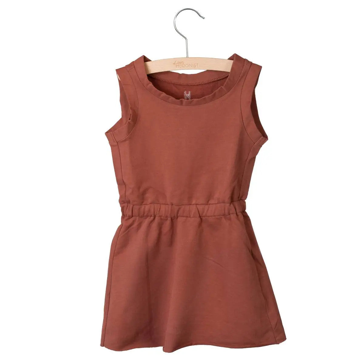 Ein ärmelloses rostfarbenes Kleid für ein Kind aus weichem Stoff, das auf einem Holzbügel vor einem weißen Hintergrund präsentiert wird. Das Kleid hat eine taillierte Passform und ein einfaches, lässiges Design.