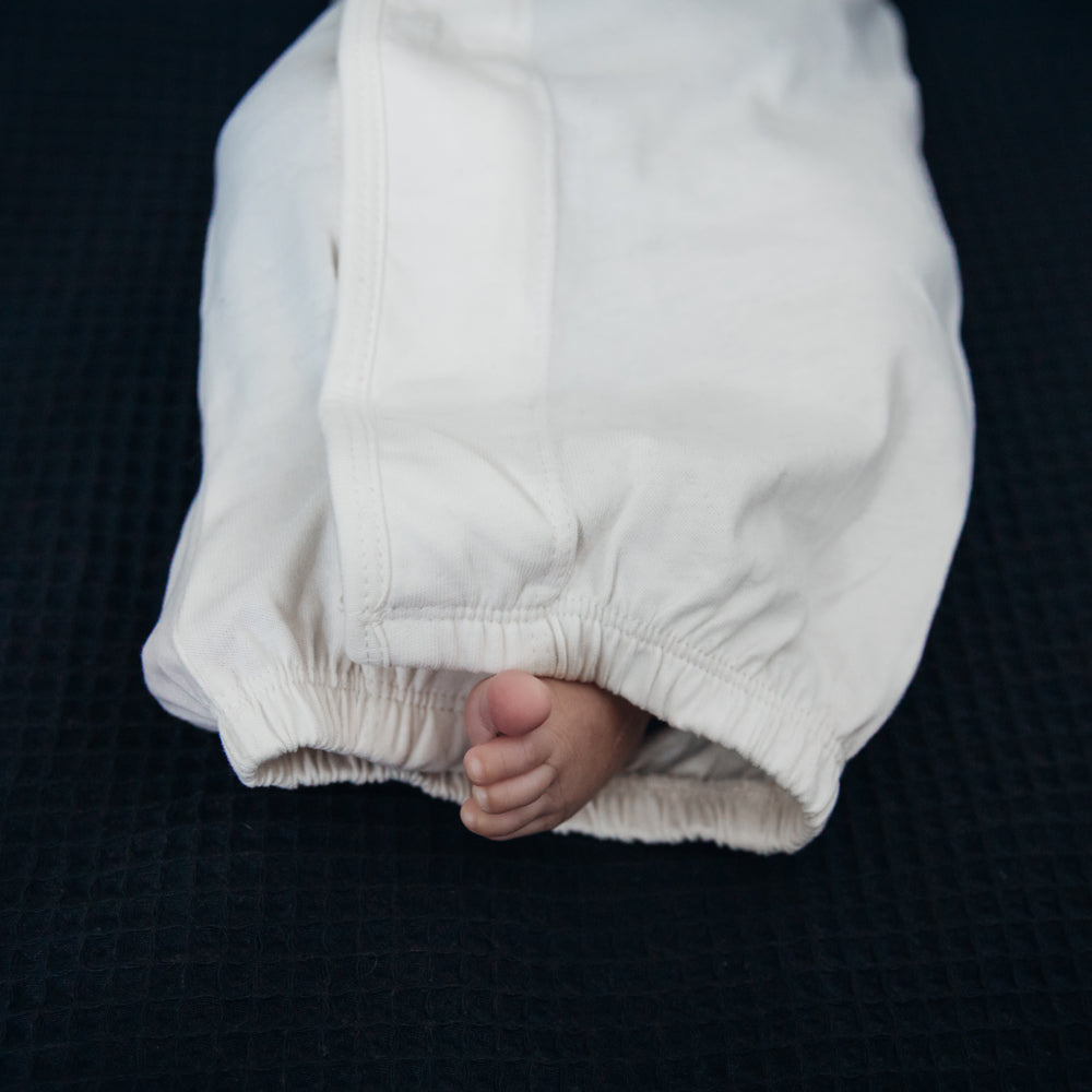 Ein Babyfuß ist in eine weiße Decke eingewickelt, die auf einem dunklen Hintergrund liegt.