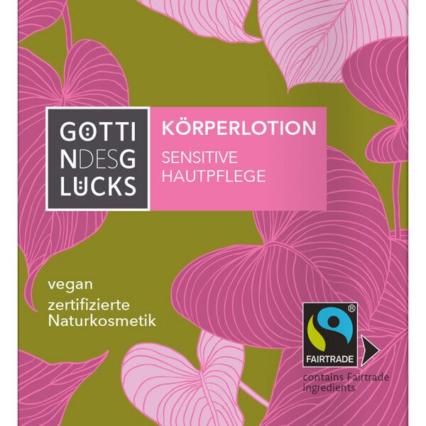 Ein Produktetikett mit rosafarbenem und grünem Blattmotiv, auf dem die Logos der Göttin des Glücks, der Körperlotion Sensitive Hautpflege, der Fairtrade- und Vegan-Zertifizierung sowie ein deutscher Text über Naturkosmetik abgebildet sind.