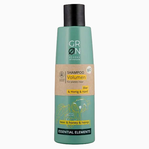 Eine grüne Flasche des GRN Shades of Nature Volumen Shampoo mit Bier, Honig und Hanf für feines Haar. Das Etikett zeigt gelbe Akzente und einfache Illustrationen von Pflanzen.