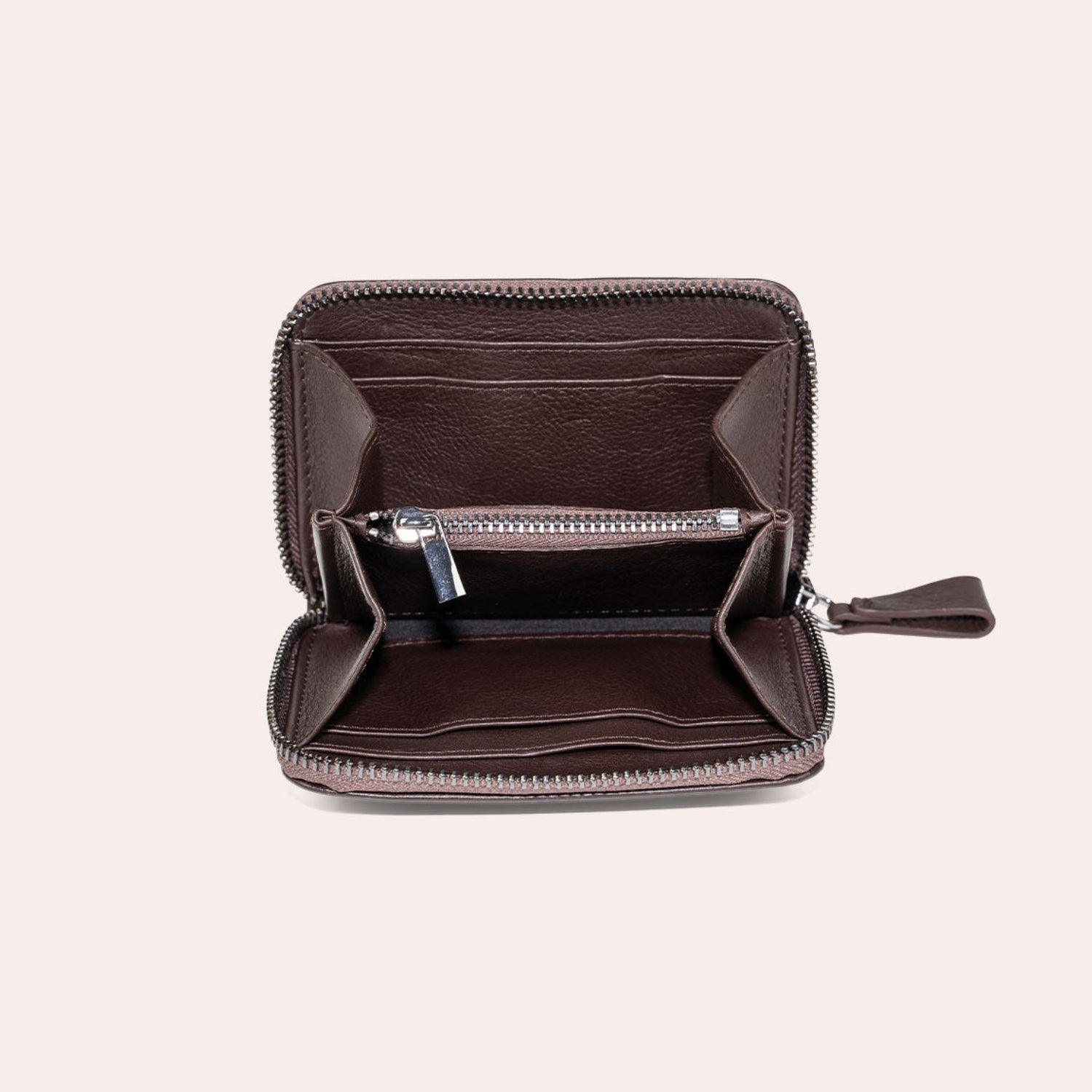 Ein kleines, offenes braunes Lederportemonnaie mit Reißverschluss, mit Fächern für Karten und einem Münzfach mit Reißverschluss, vor einem schlichten hellen Hintergrund.