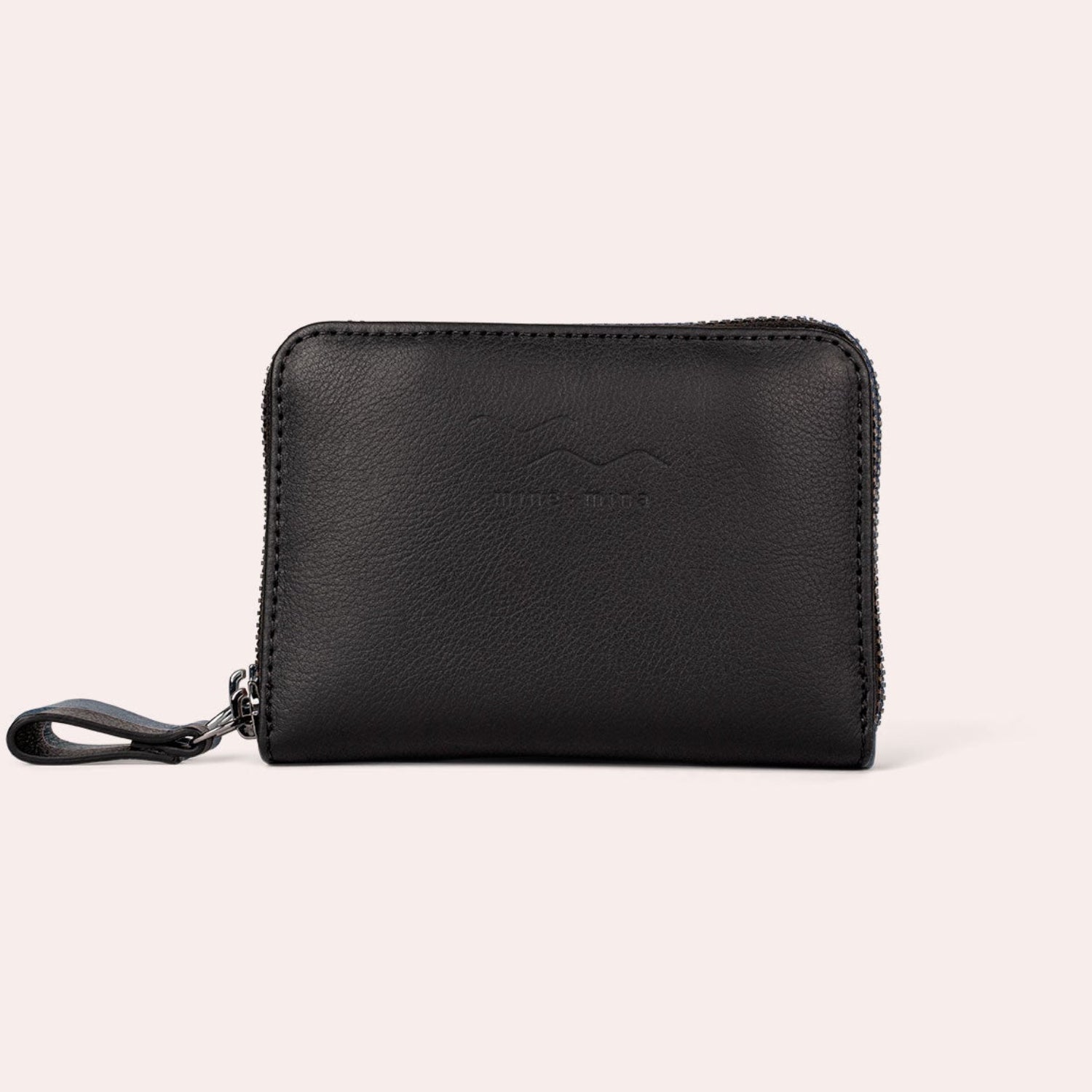 Ein kleines schwarzes Portemonnaie aus Leder mit Reißverschluss und einer Handschlaufe, das sich vor einem schlichten, hellen Hintergrund präsentiert. Das Portemonnaie hat ein dezentes, geprägtes Branding auf der Vorderseite.