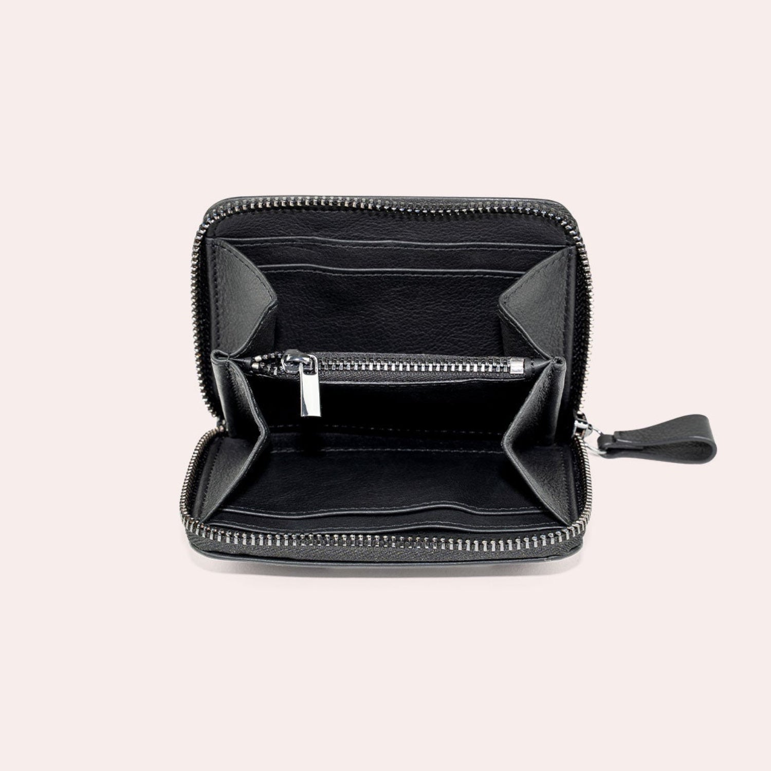 Eine schwarze Brieftasche mit Reißverschluss ist geöffnet und zeigt mehrere Fächer und eine zentrale Reißverschlusstasche, die vor einem schlichten hellen Hintergrund dargestellt sind.
