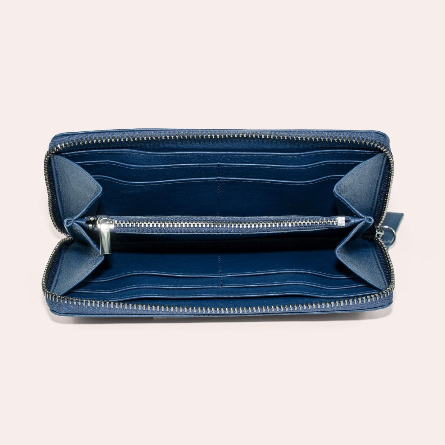 Eine offene blaue Brieftasche mit Reißverschluss mit mehreren Kartenfächern und einem zentralen Münzfach mit Reißverschluss, abgebildet auf einem hellbeigen Hintergrund.