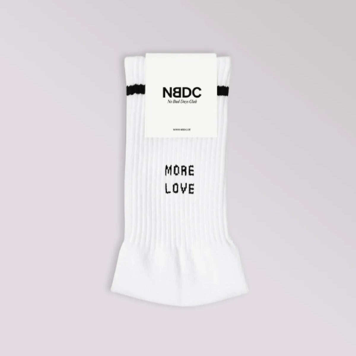 Ein Paar weiße Socken mit einem schwarzen Streifen am oberen Ende, verpackt mit einem Etikett mit der Aufschrift N8DC. Auf der Vorderseite der Socken sind in schwarzen Buchstaben die Worte MORE LOVE aufgedruckt. Der Hintergrund ist hellgrau.