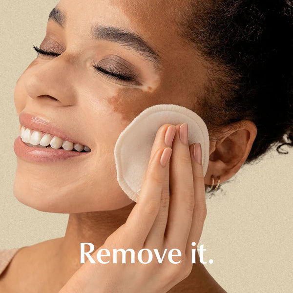 Eine Frau mit Vitiligo lächelt, während sie ihr Gesicht sanft mit einem wiederverwendbaren Wattepad reinigt. Am unteren Rand des Bildes erscheint der Schriftzug Remove it.