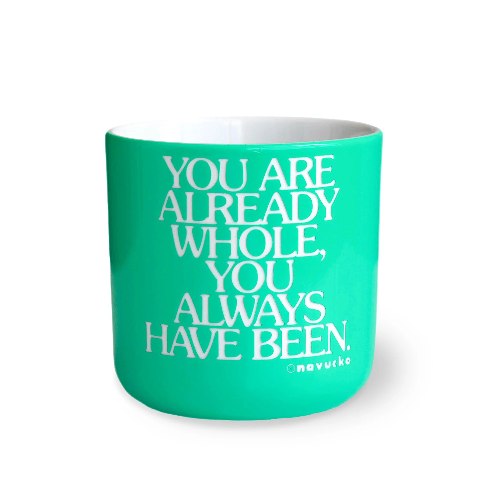 Ein türkisfarbener Becher mit weißem Text, der lautet: Du bist bereits ganz, du warst es schon immer. Omavucko auf der Vorderseite. Der Becher ist auf einem weißen Hintergrund fotografiert.