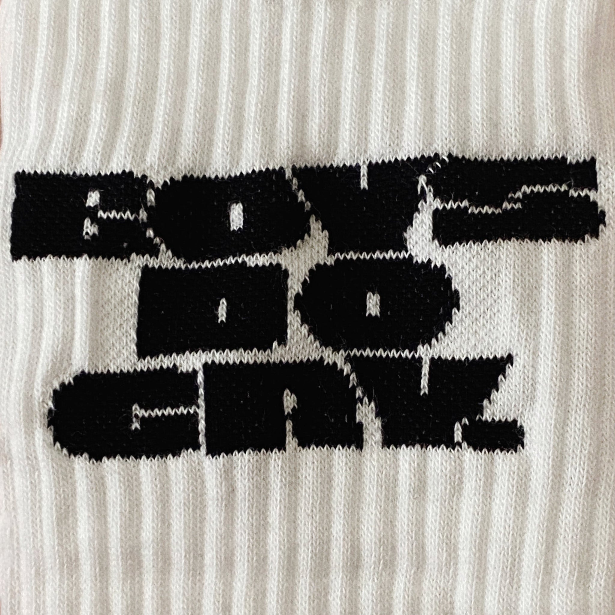 Schwarzer Text "BOYZ DO CRYZ" auf weißem, geripptem Strickstoff.