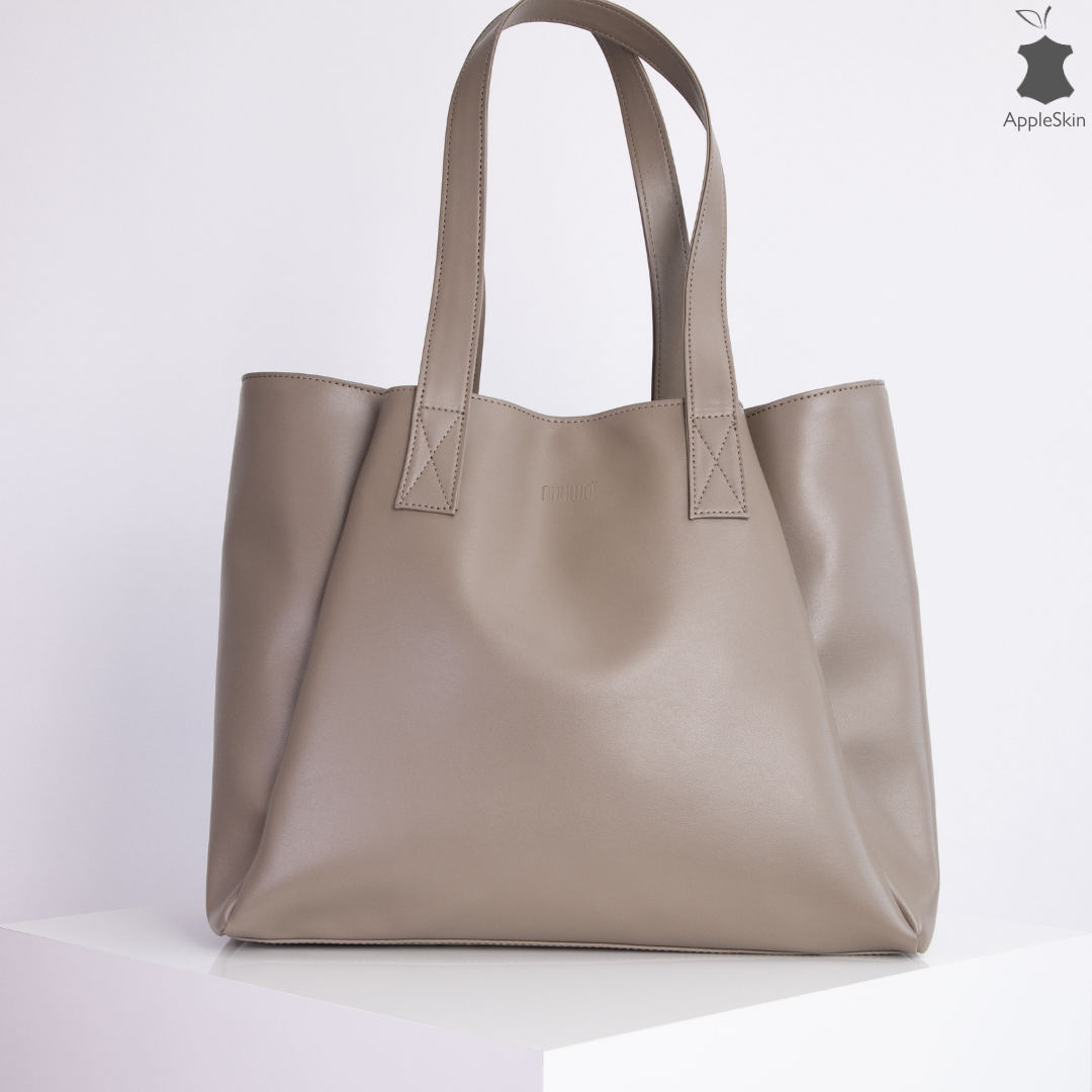Hellbraune Handtasche aus glattem Material mit zwei Griffen, auf einem weißen Podest präsentiert.