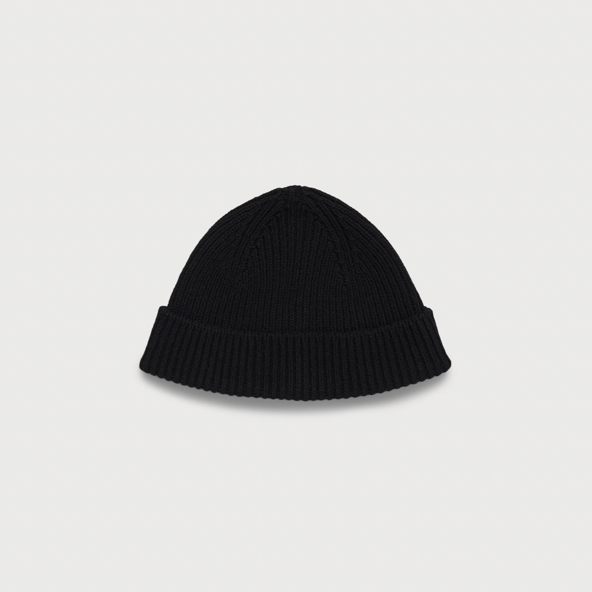 Schwarze Strickmütze mit Umschlag auf weißem Hintergrund.