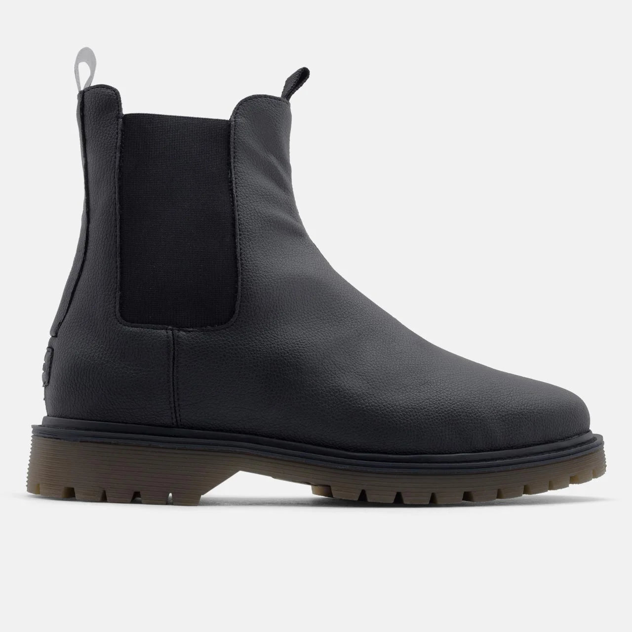 Ein schwarzer Chelsea-Stiefel mit strukturiertem Obermaterial aus Leder, elastischen Seiteneinsätzen, einer Zuglasche hinten und einer klobigen braunen Gummisohle, im Profil auf einem einfarbig weißen Hintergrund.