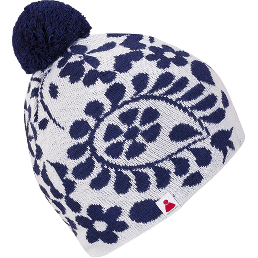 Weiße Strickmütze mit dunkelblauem Blumenmuster und dunkelblauem Bommel. Auf der Vorderseite befindet sich ein kleiner Anhänger mit einem rot-grünen Logo.