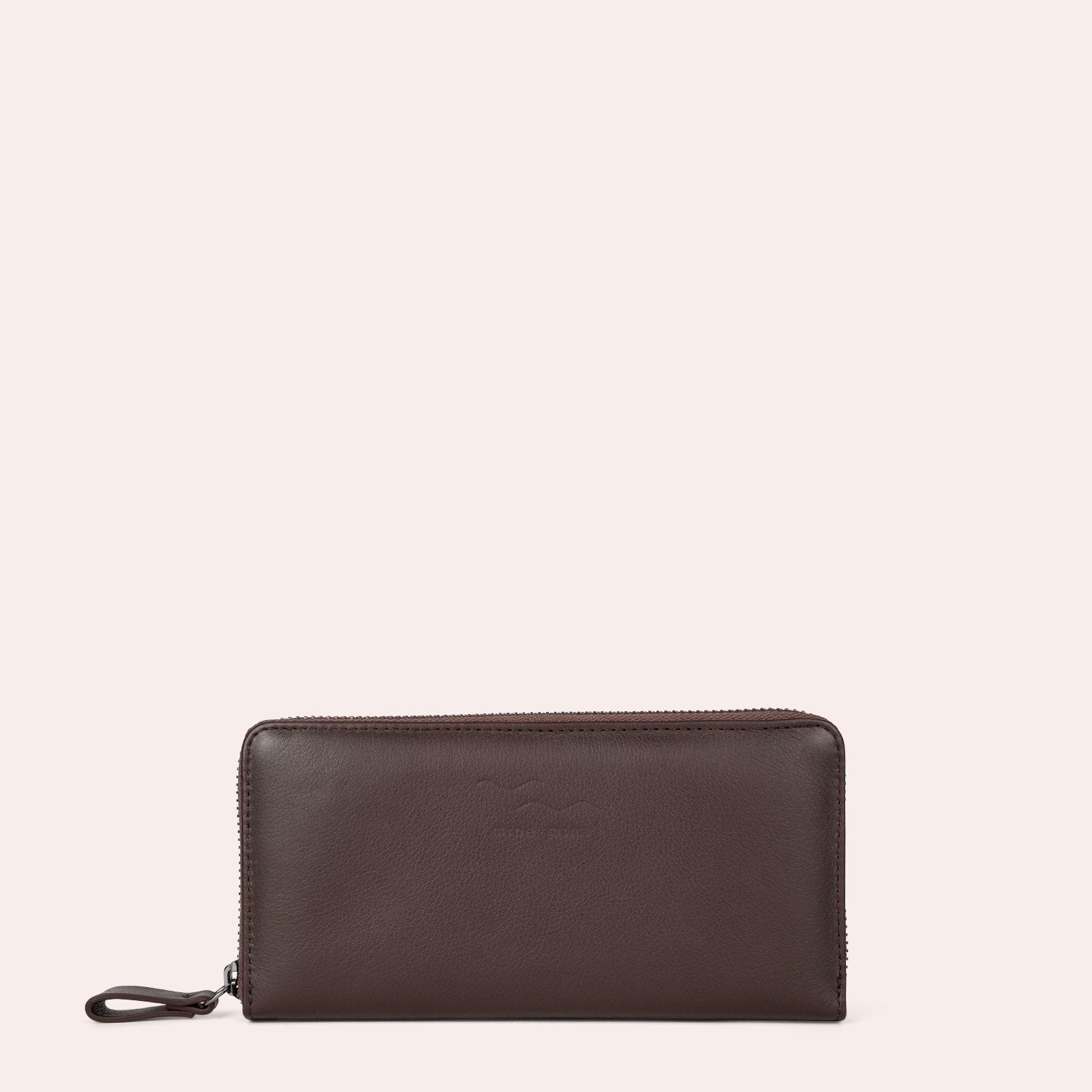 Ein braunes Lederportemonnaie mit Reißverschluss und Handschlaufe vor einem schlichten, hellen Hintergrund.