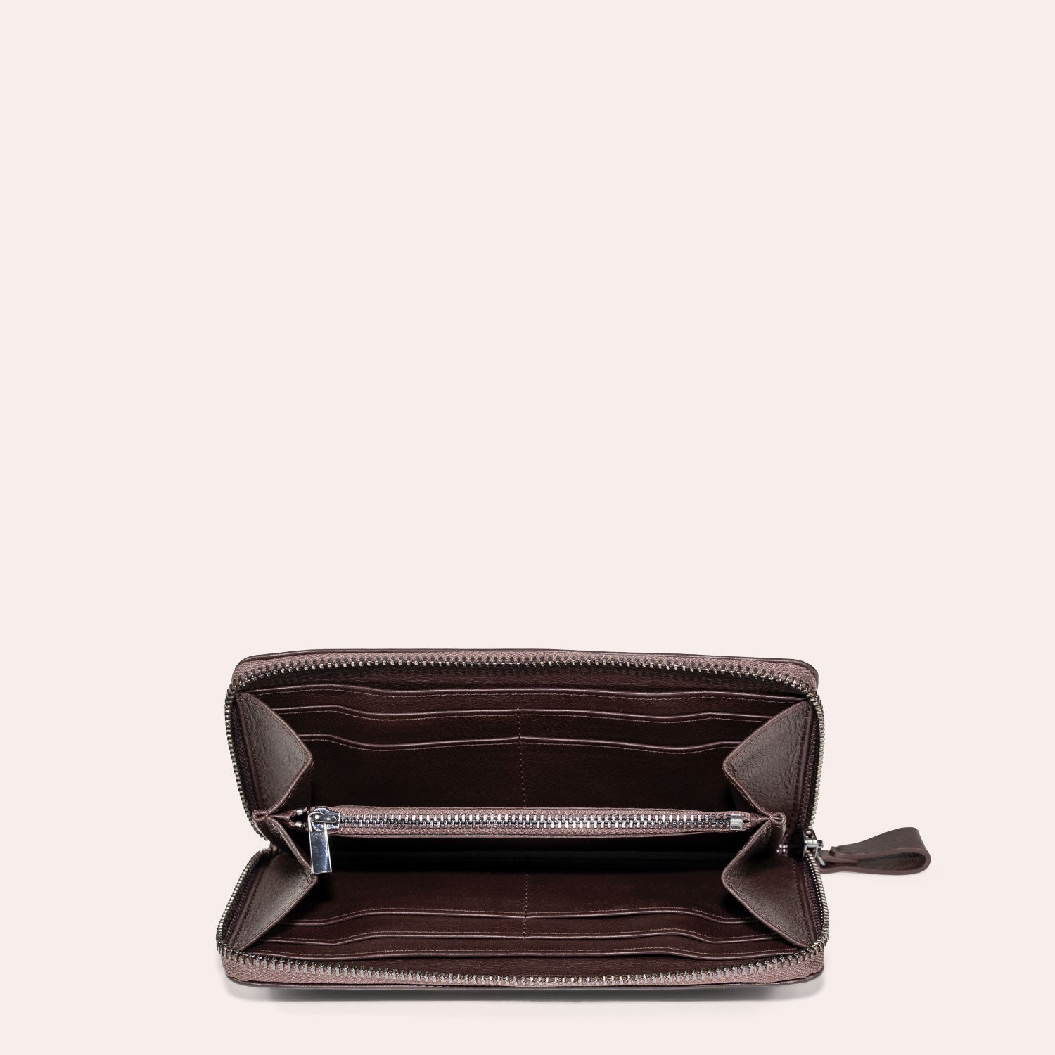 Offene braune Ledergeldbörse mit Reißverschluss und mehreren Fächern und Kartenschlitzen, von oben auf einem schlichten hellen Hintergrund fotografiert.
