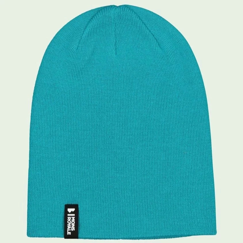 Türkisblaue Strickmütze mit einem kleinen, schwarzen Etikett an der Unterseite auf hellem Hintergrund.