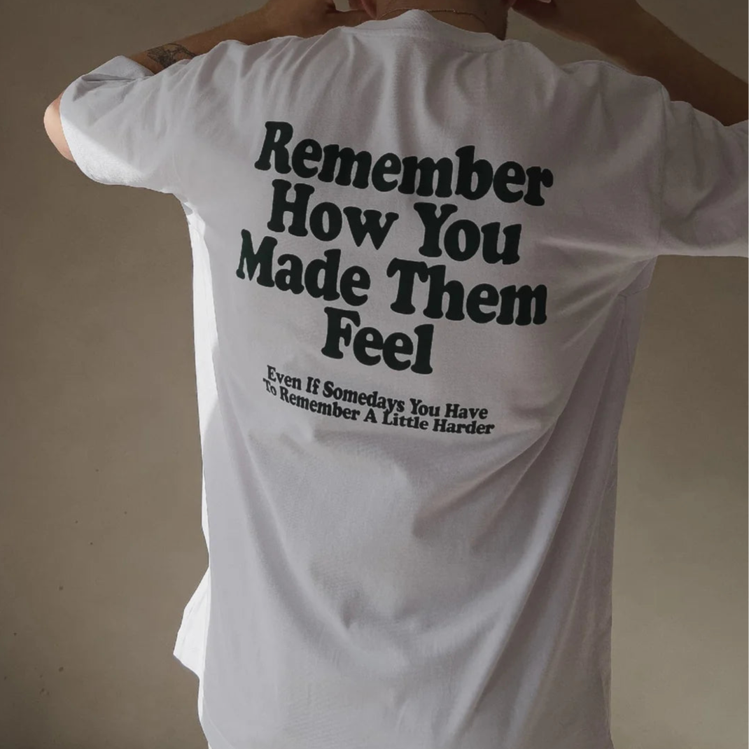 Rückenansicht einer Person in einem weißen T-Shirt mit schwarzem Text: "Remember How You Made Them Feel, Even If Somedays..."
