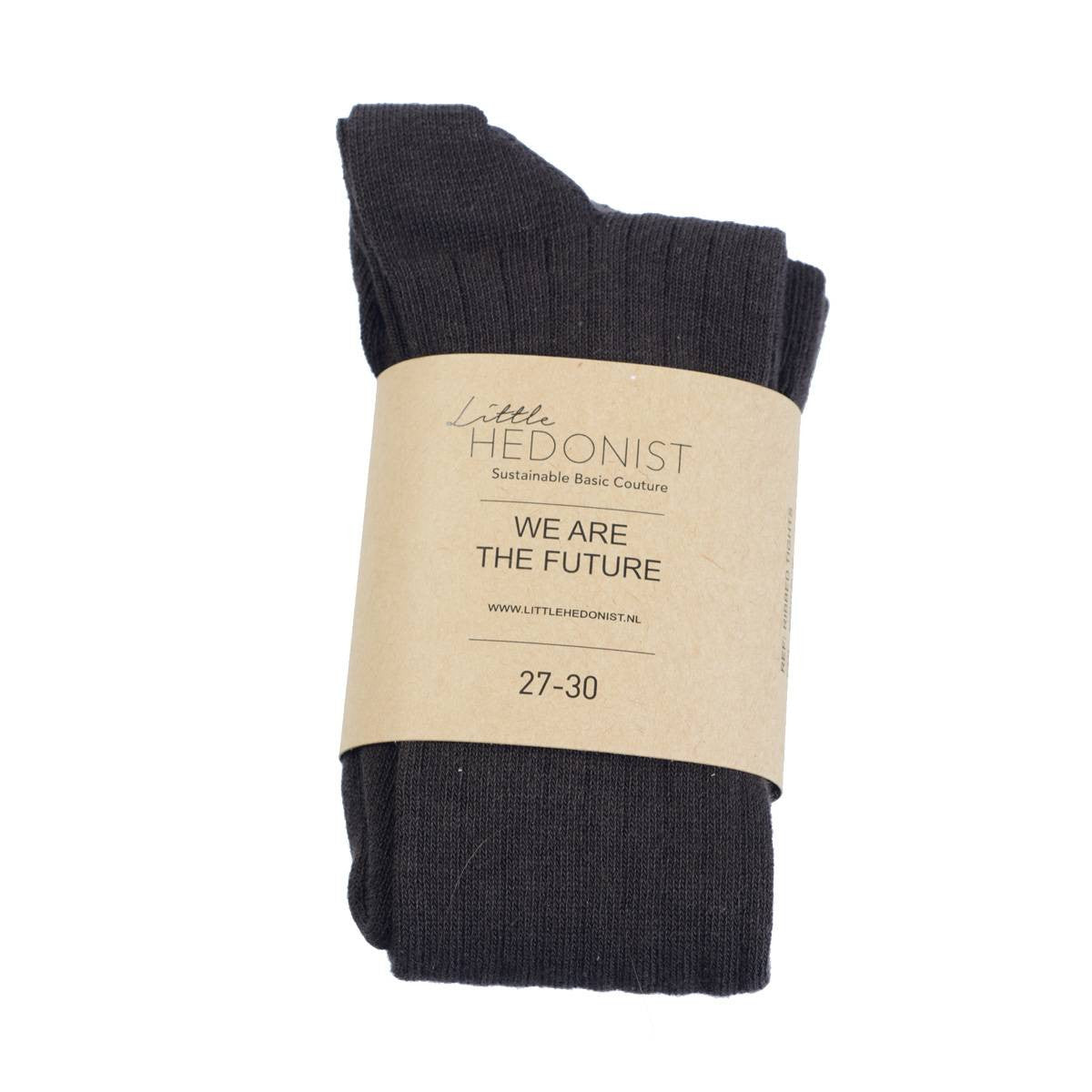 Ein Paar schwarze Socken, eingewickelt in ein braunes Papieretikett mit der Aufschrift Little Hedonist Sustainable Basic Couture. WIR SIND DIE ZUKUNFT. 27-30.