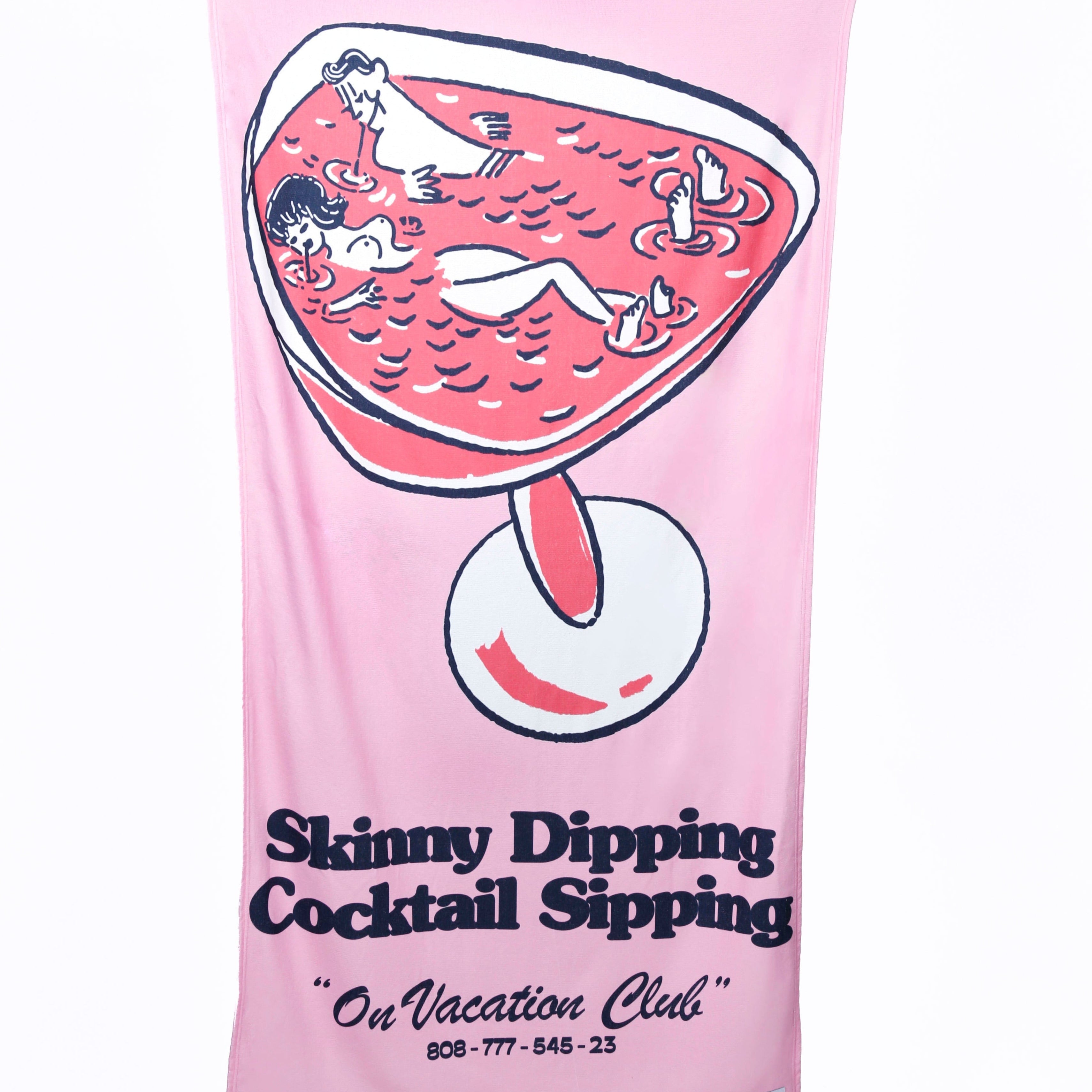 Eine Person hält ein rosafarbenes Handtuch hoch, auf dem zwei Personen abgebildet sind, die sich in einem Cocktailglas entspannen. Der Text lautet: Skinny Dipping Cocktail Sipping On Vacation Club 808-777-545-23.
