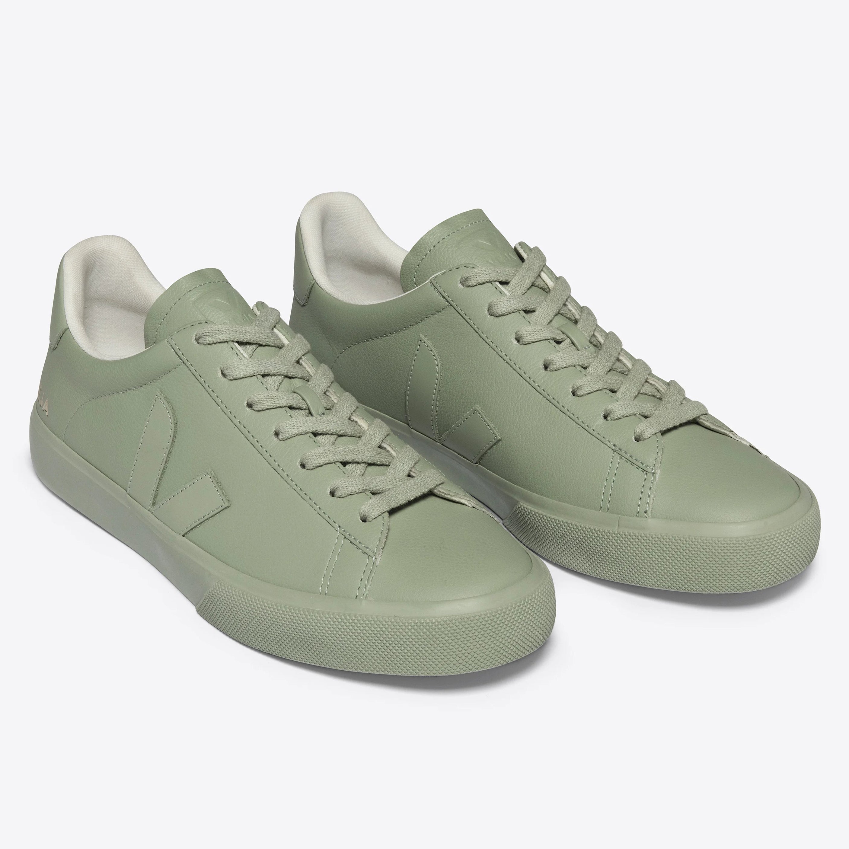 Ein Paar hellgrüne Low-Top-Sneakers mit passenden Schnürsenkeln und weißem Innenfutter, dargestellt auf einem schlichten hellgrauen Hintergrund.