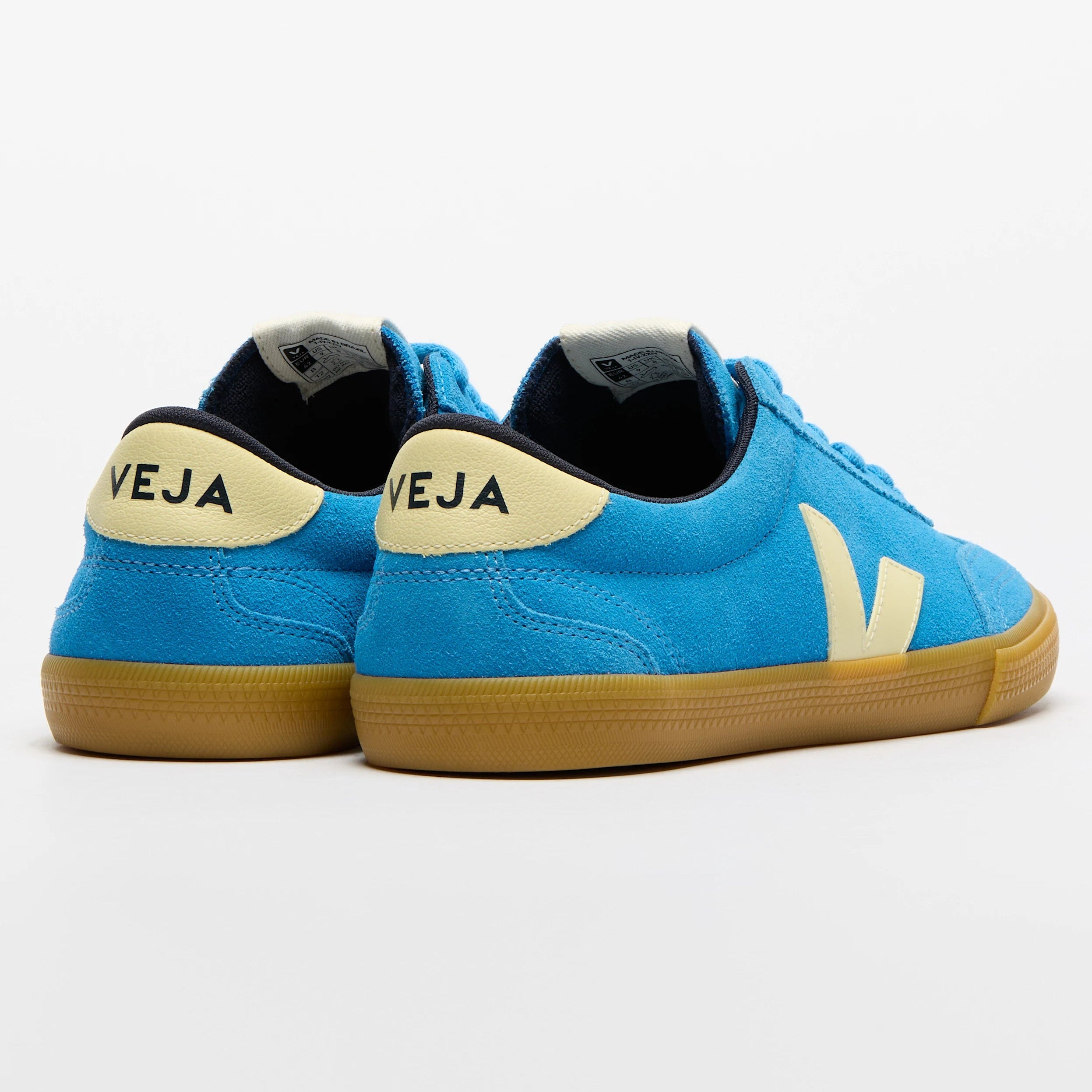 Ein Paar blaue Veja-Turnschuhe mit cremefarbenen Fersenlaschen und Logos sowie Gummisohlen, dargestellt von hinten und von der Seite auf weißem Hintergrund.