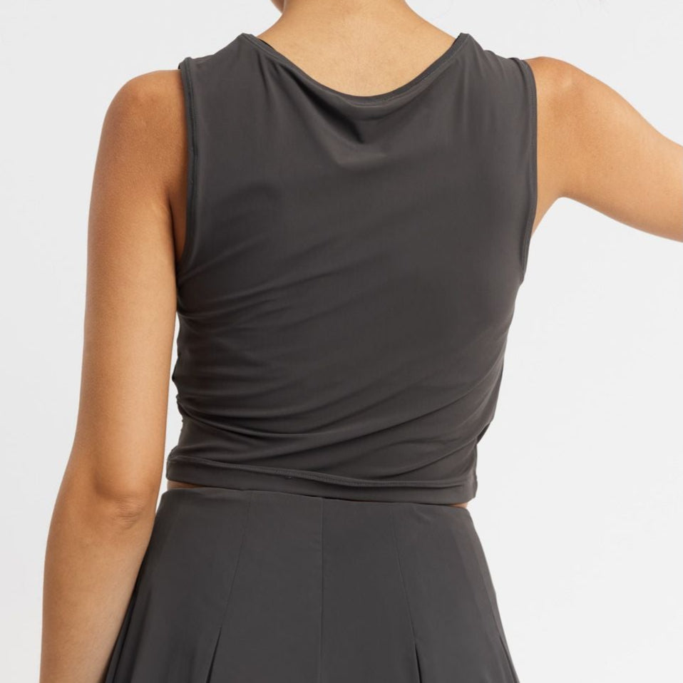 Person in a dark sleeveless top and skirt, seen from the back.