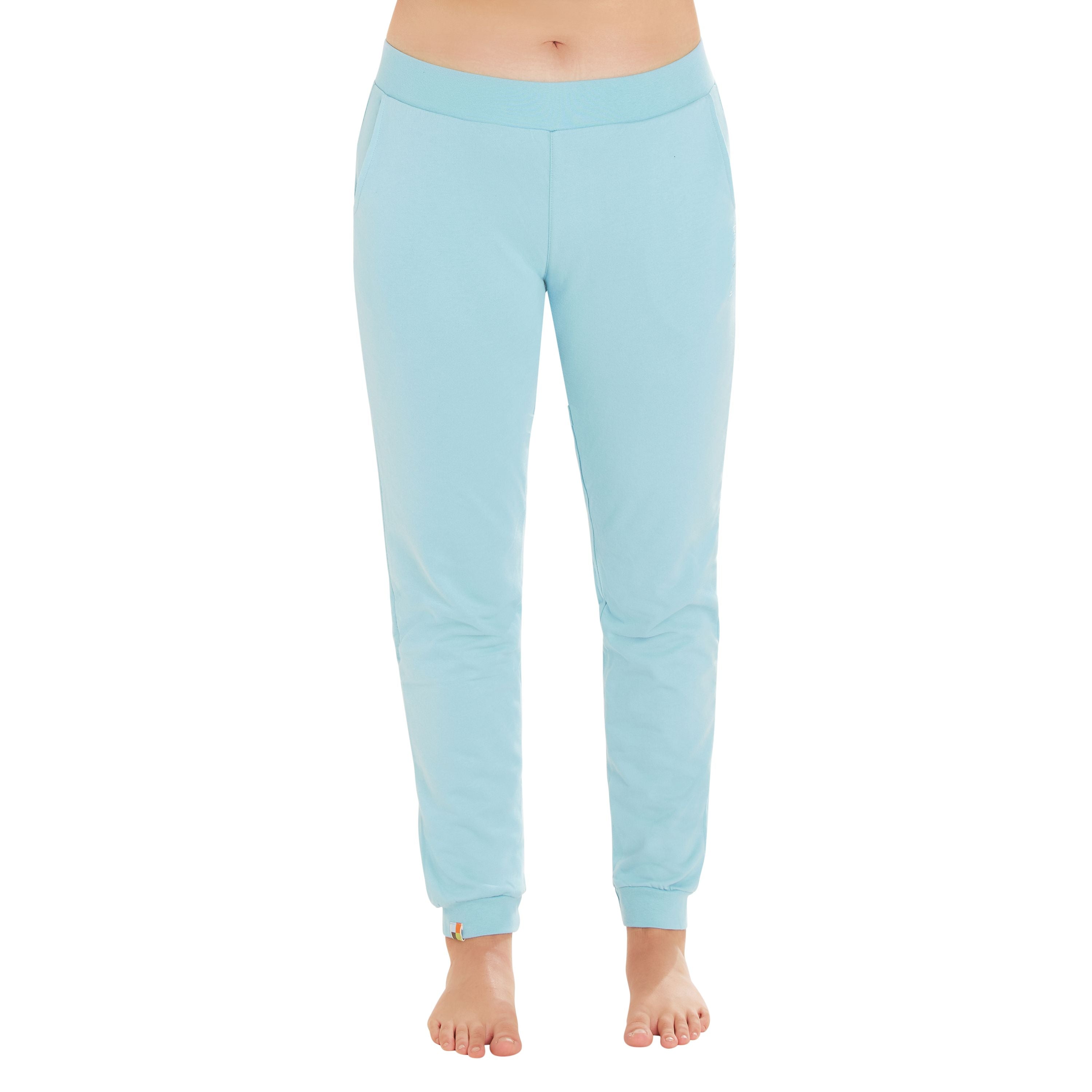 Eine Person in hellblauer Jogginghose steht barfuß vor einem weißen Hintergrund. Die Hose hat einen elastischen Bund und Bündchen an den Knöcheln. Der Oberkörper der Person ist nicht sichtbar.