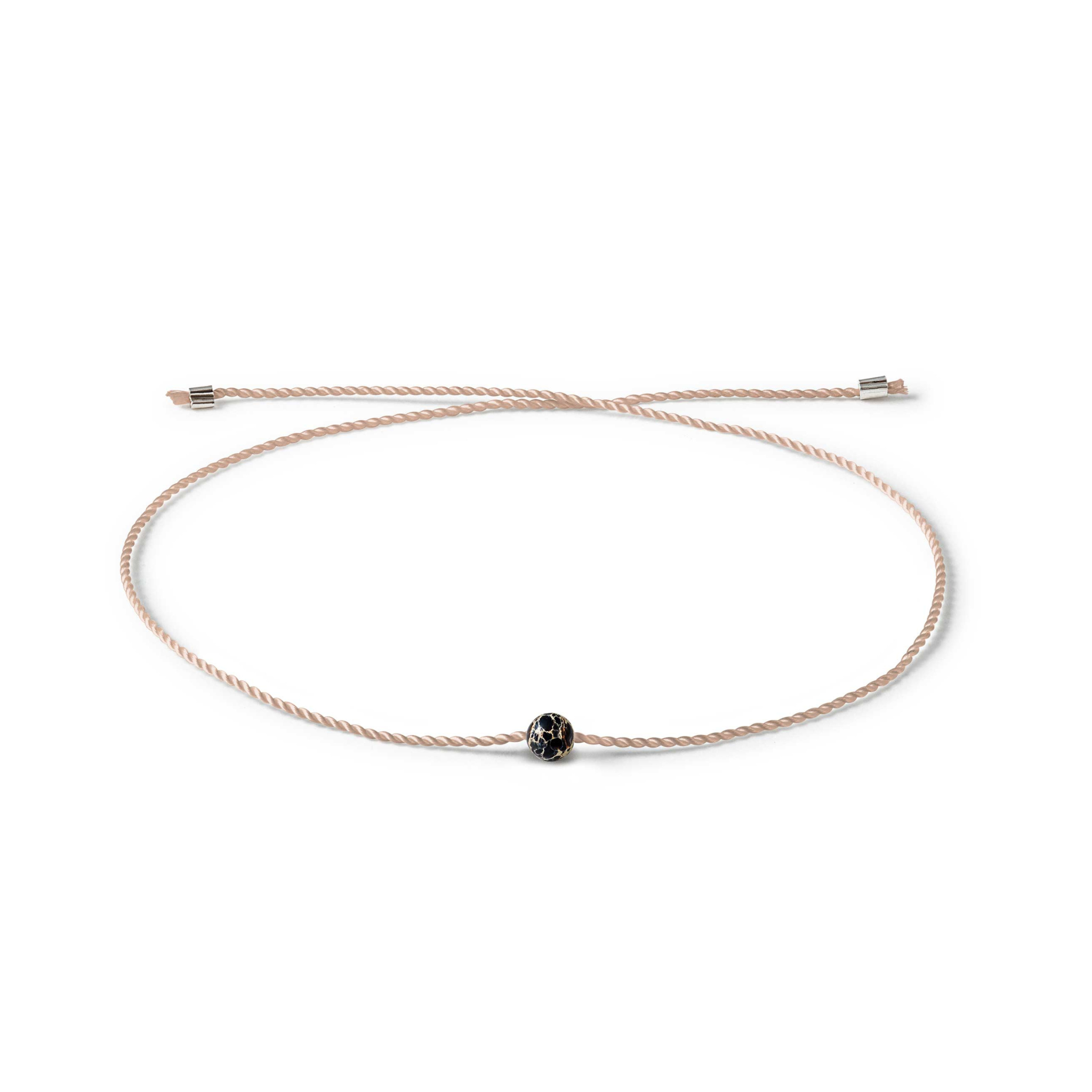 Hellbraunes Armband mit schwarzem, goldakzentuiertem Stein, filigran gestaltet, auf weißem Hintergrund.