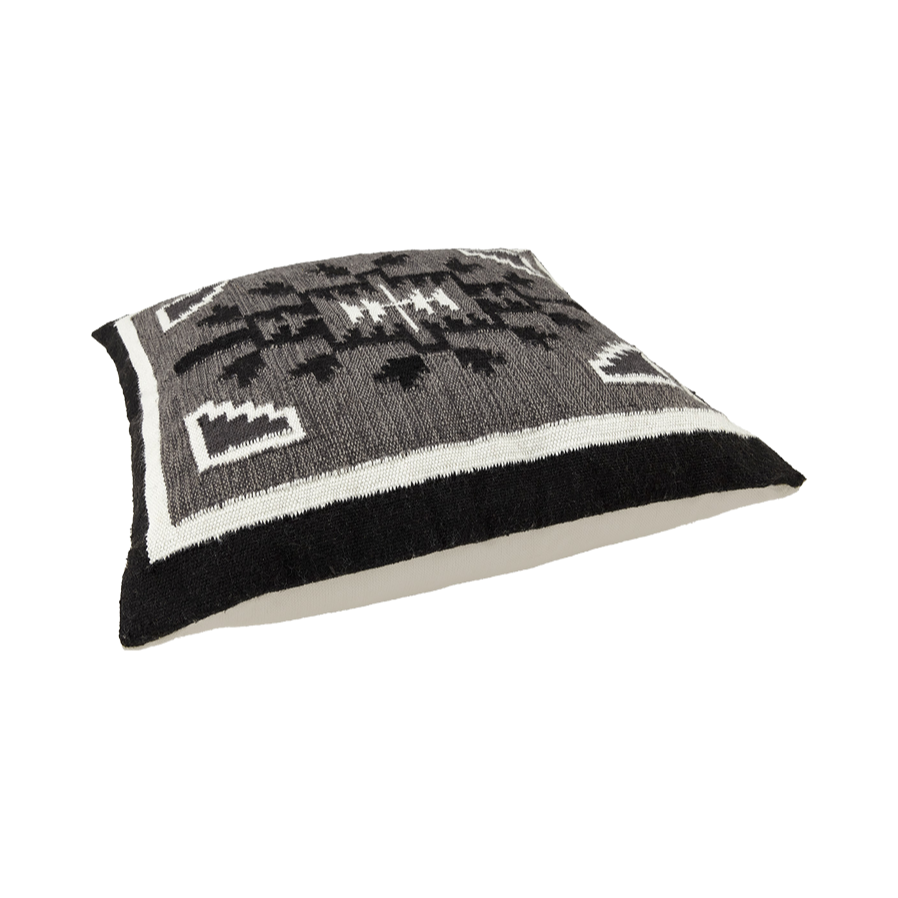 Ein quadratisches Kissen mit einem schwarzen, grauen und weißen geometrischen Muster auf der Oberseite und einem einfarbigen weißen Stoff auf der Seite, dargestellt vor einem weißen Hintergrund.