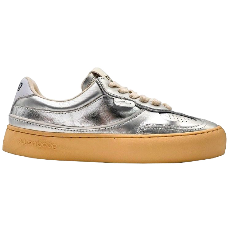 Ein silbermetallicfarbener Low-Top-Sneaker mit beigen Schnürsenkeln und einer dicken hellbraunen Gummisohle auf einem schlichten weißen Hintergrund.