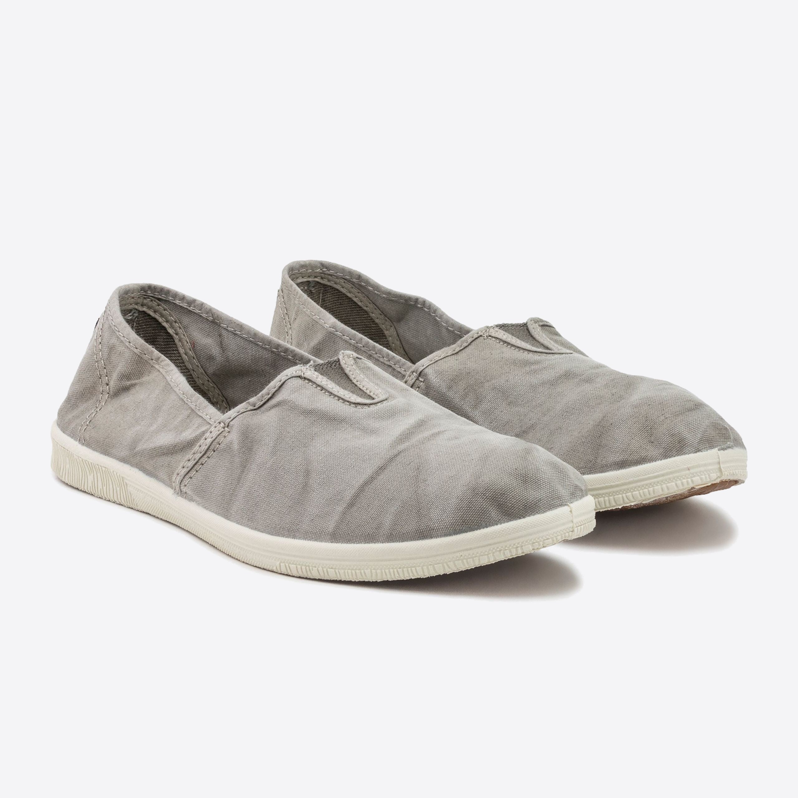 Graue Stoffslipper mit weißer Gummisohle, auf hellem Hintergrund fotografiert.