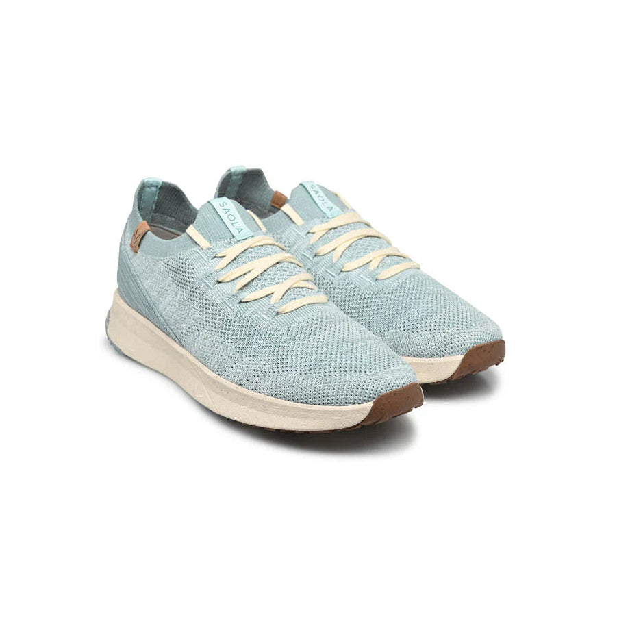 Ein Paar hellblaue Sportschuhe mit gewebter Textur, beigen Schnürsenkeln und weißen Sohlen. Die Schuhe haben braune Akzente an der Ferse und an der Spitze und sind nebeneinander angeordnet, leicht nach rechts gerichtet.
