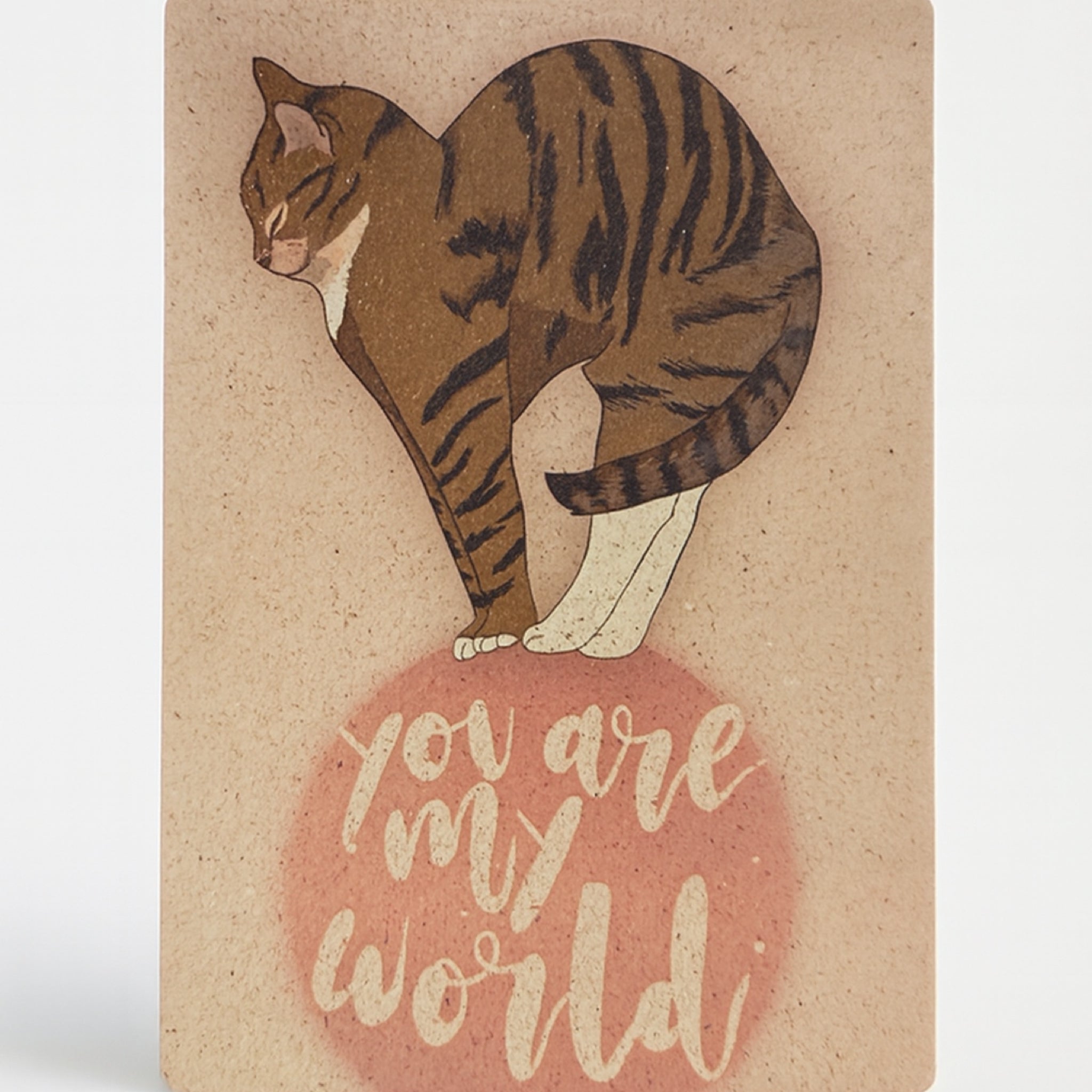 Eine Grußkarte mit einer Illustration einer getigerten Katze, die über dem handgeschriebenen Satz "You are my world" in weißer Schrift auf einem rosa Kreis steht.