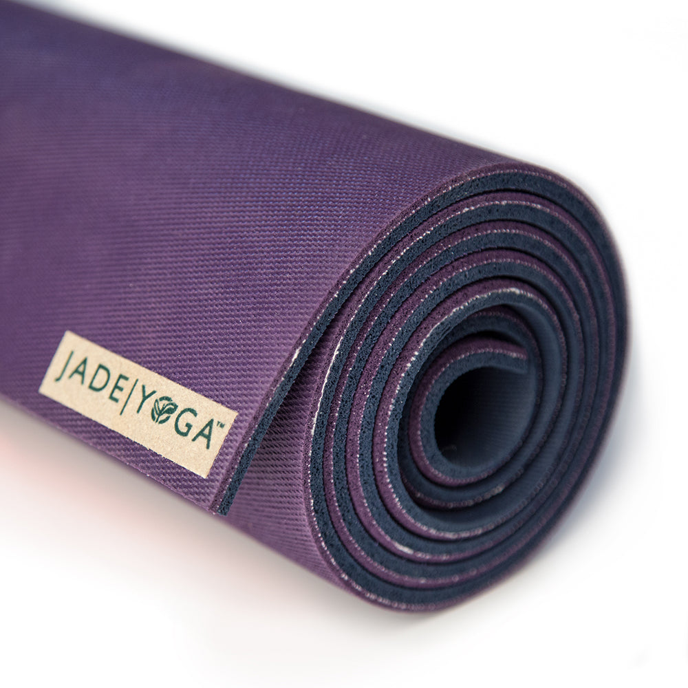 Lila Yogamatte von JadeYoga, aufgerollt und seitlich fotografiert, mit einem Markenlabel sichtbar.